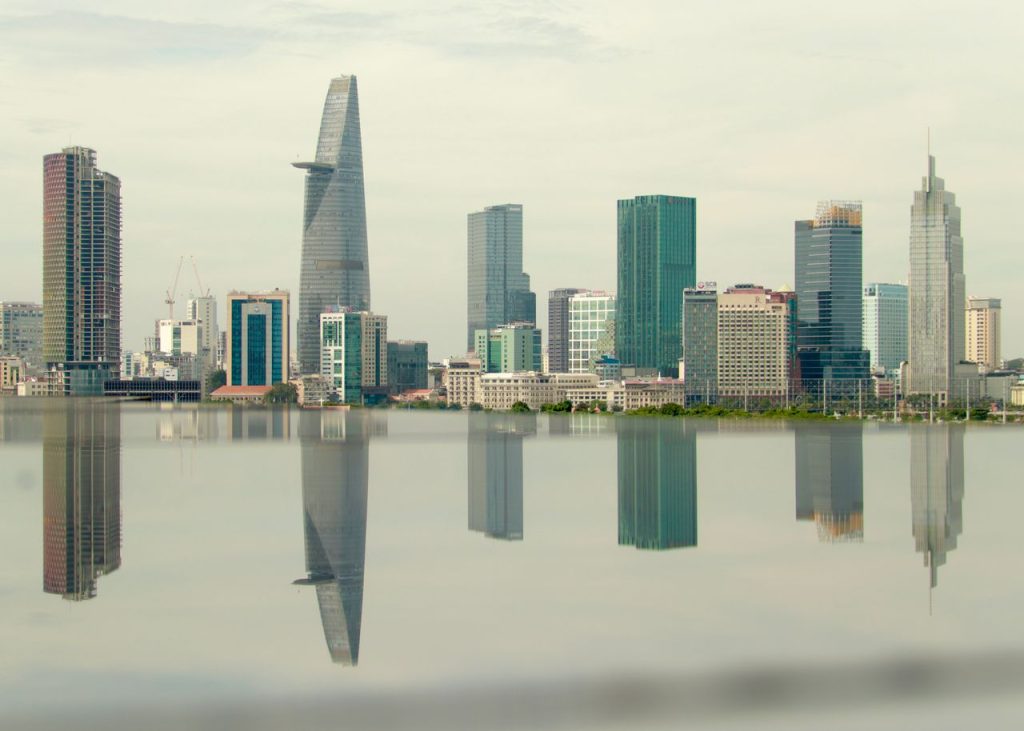 Skyline of Ho Chi Minh City with skyscrapers reflected in the Saigon River.