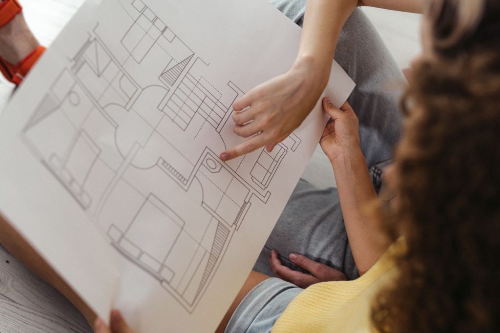 Two people reviewing and discussing a detailed architectural floor plan.